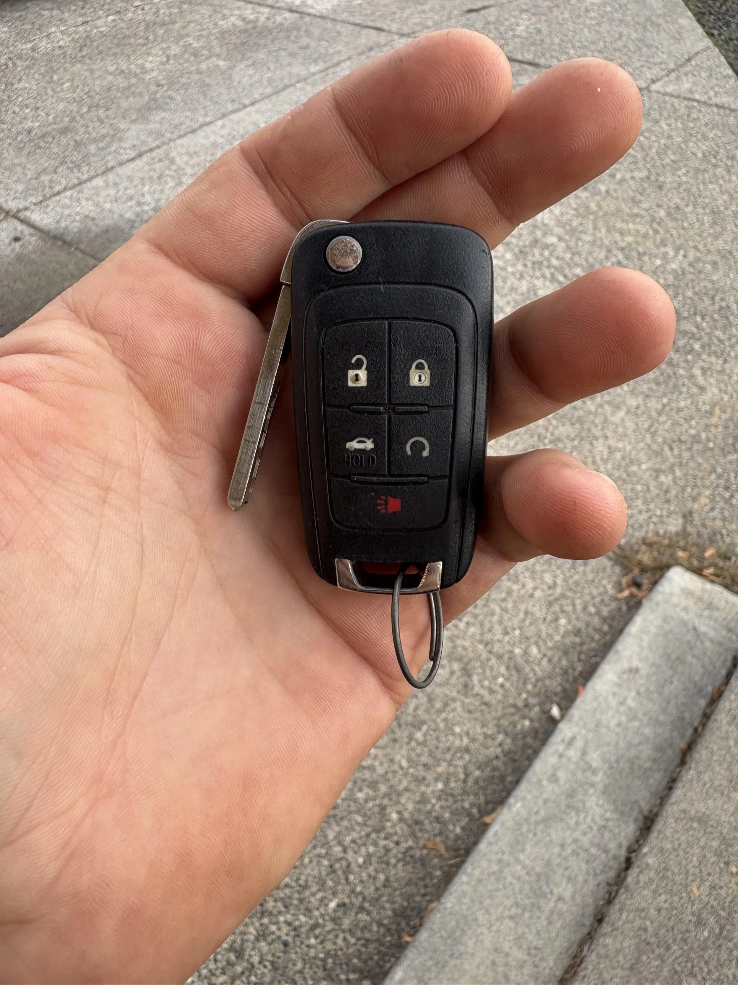 Damaged car key and replacement blanks on a workbench.